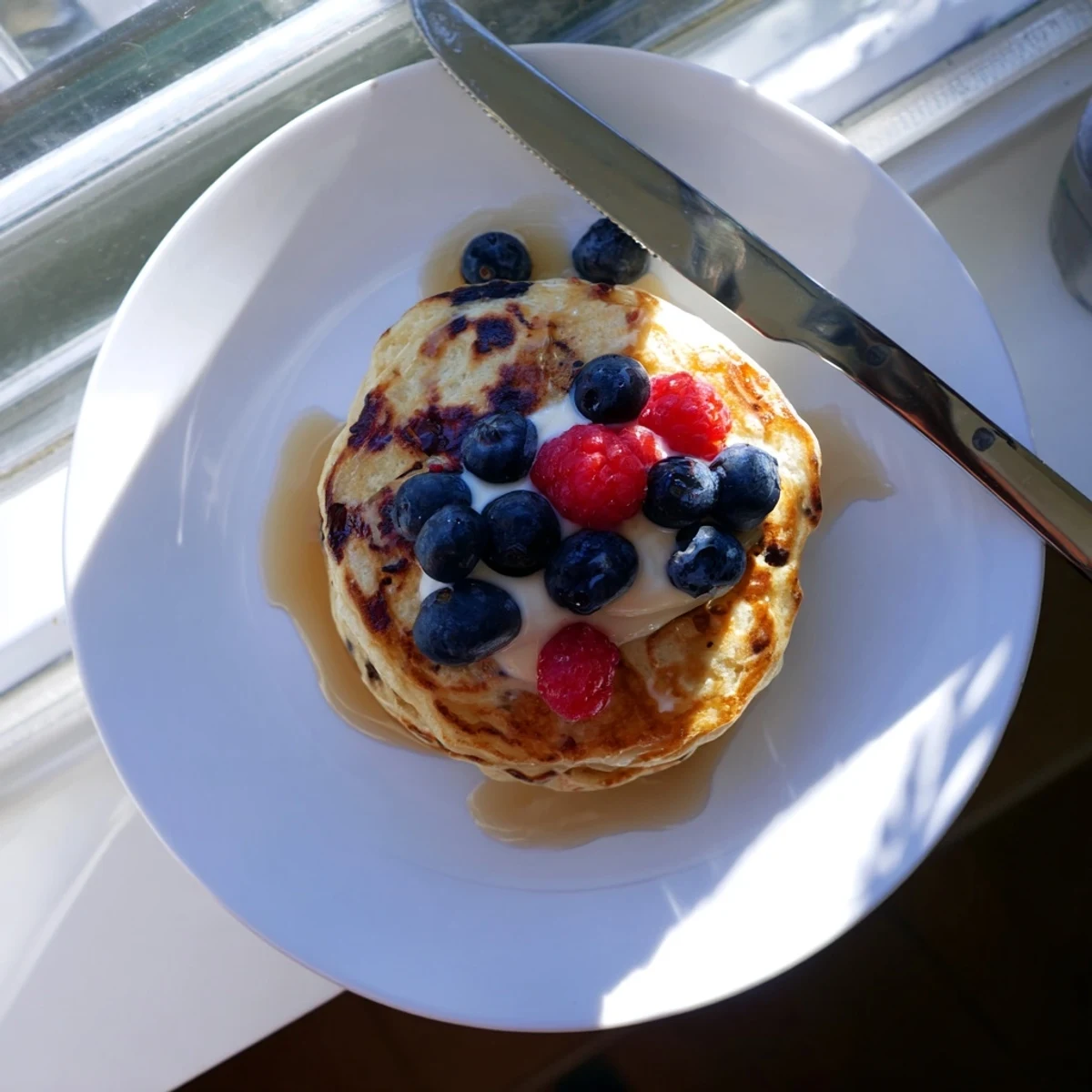 Fluffy cottage cheese pancakes stacked high, topped with fresh berries and a drizzle of maple syrup for a protein-rich breakfast.