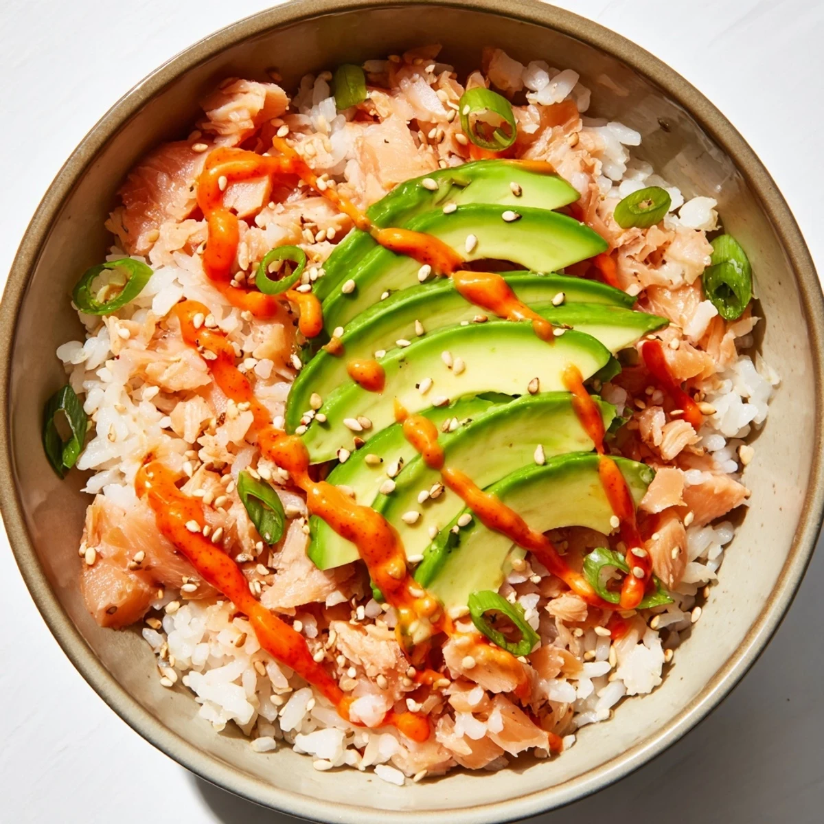 Vibrant Emily Mariko Salmon Rice Bowl with flaked salmon, creamy avocado slices, and spicy mayo drizzle.