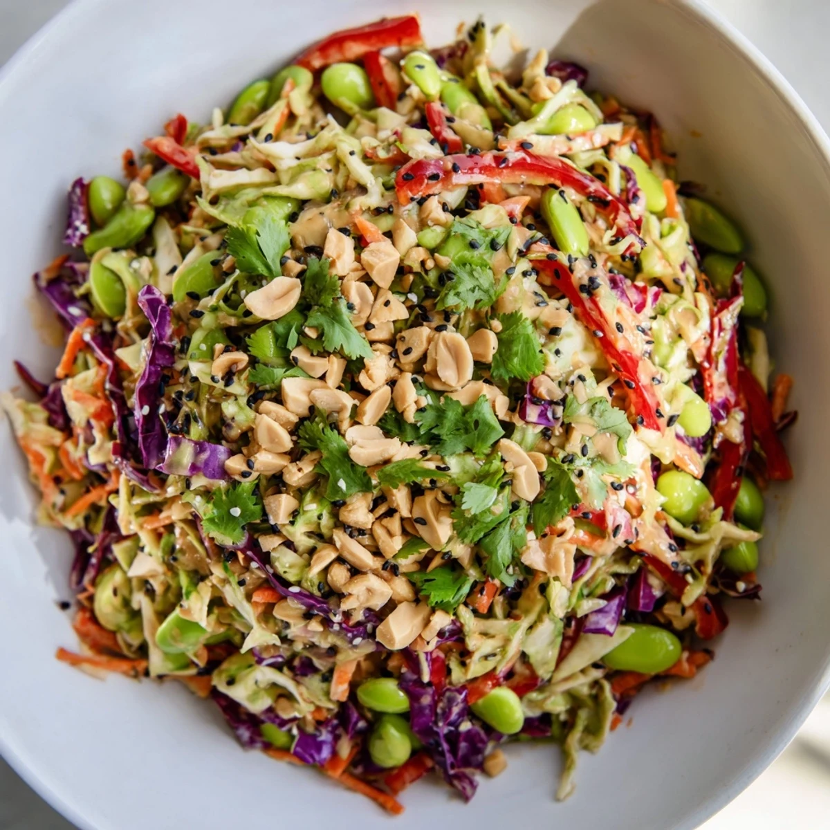 Easy vegetarian Crunchy Thai Peanut Salad featuring crisp veggies and a smooth peanut sauce, garnished with fresh cilantro and sesame seeds.