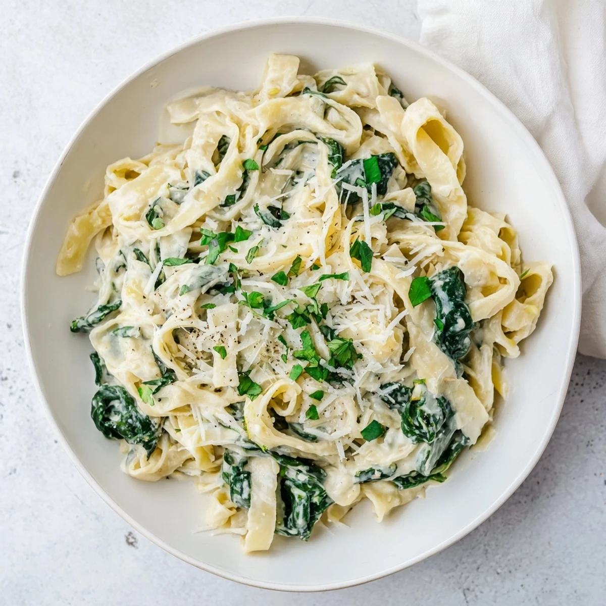 Close-up of Creamy Garlic Spinach Pasta twirled on a fork, showcasing the luscious garlic cream coating the fettuccine.