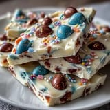 Colorful Easter chocolate bark with pastel swirls, Cadbury eggs, and sprinkles on a white chocolate base.