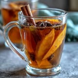 Warm cup of dandelion root tea with ginger and turmeric, garnished with a slice of lemon and a drizzle of honey.