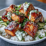Vibrant salmon rice bowl featuring spicy mayo drizzle, fresh cucumber slices, and toasted sesame garnish for a satisfying meal.