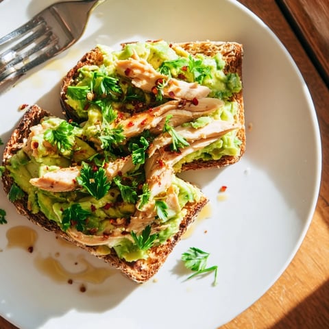 Golden-brown toasted sourdough topped with creamy smashed avocado and juicy grilled chicken slices, finished with a honey drizzle and chili flakes for this savory-sweet Smashed Avocado Chicken Toast.