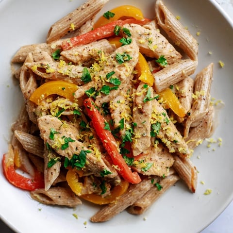 Creamy Cajun Chicken Pasta Lite served in a white bowl with steaming penne, colorful bell peppers, and fresh parsley garnish.