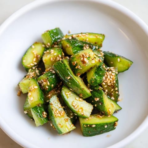 A chilled Cucumber Shaker salad, exploding with umami flavor, topped with sesame seeds.