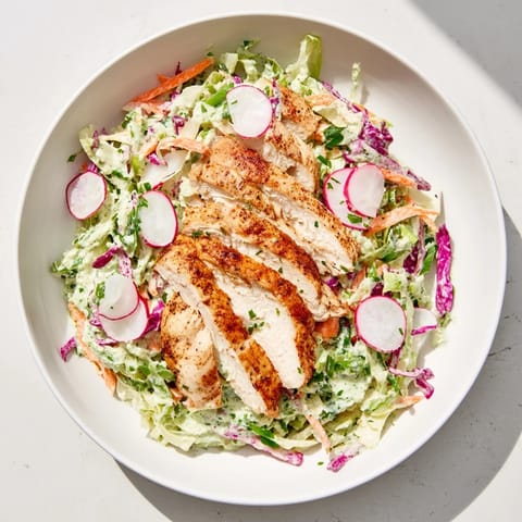 This photo highlights a fresh, bright Green Goddess Cabbage Slaw beautifully topped with grilled chicken slices.