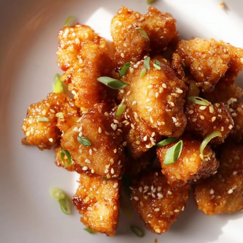 Crispy and flavorful Honey-Sriracha Chicken Bites, a perfect appetizer, served with sesame seeds, a true delight.