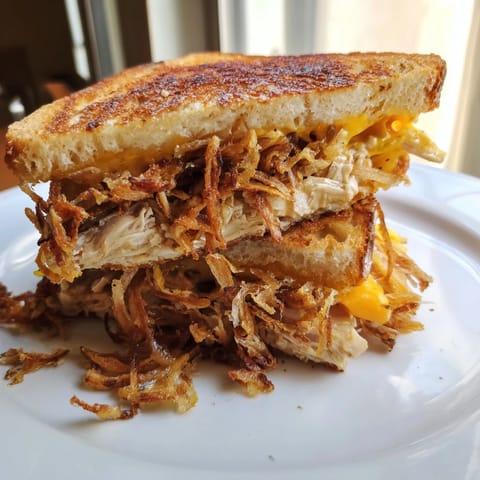Mouthwatering image of a Crispy Shallot Chicken Grilled Cheese, showing a melty cheese pull, delicious.