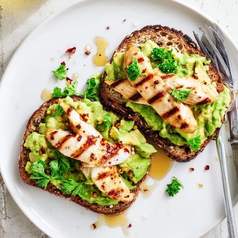 Golden-brown toasted sourdough topped with creamy smashed avocado and juicy grilled chicken slices, finished with a honey drizzle and chili flakes for this savory-sweet Smashed Avocado Chicken Toast.