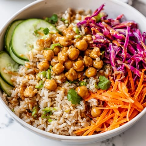 A close-up of a vibrant Peanut Chickpea Rice Bowl with colorful shredded carrots and red cabbage.