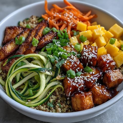 Golden-baked tofu cubes, spiralized zucchini, and sweet mango pieces shine in this Easy Teriyaki Quinoa Bowl.