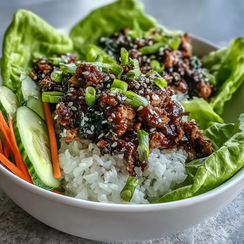 A deconstructed view of a healthy Sesame Turkey Lettuce Wrap Bowl, showcasing vibrant carrots, fresh herbs, and a savory Korean-inspired sauce drizzled over rice.