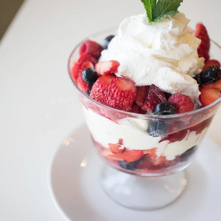 Vibrant photo of a Berry Parfait showcasing layers of berries with fluffy homemade whipped cream.
